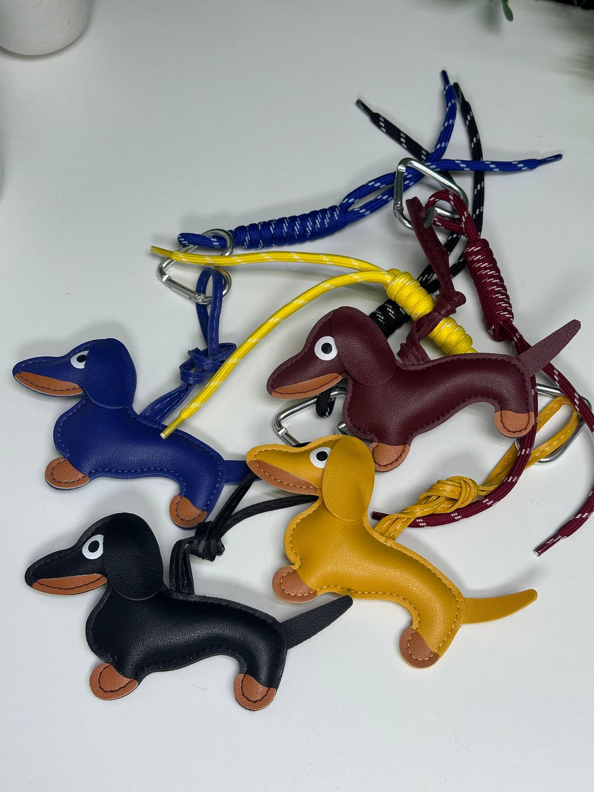 Four dachshund-shaped keychains in blue, brown, black, and yellow on a white background.