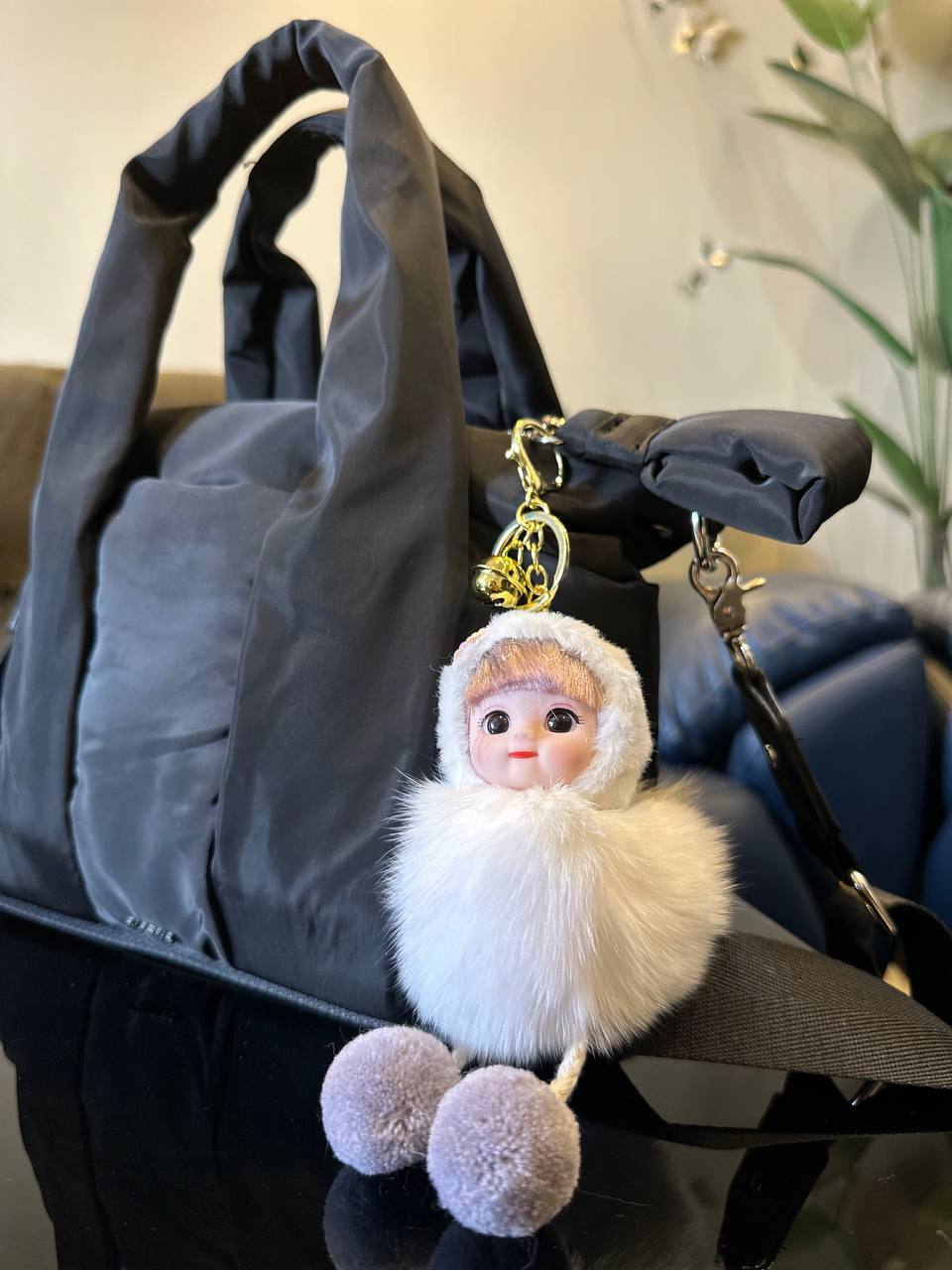 Plush keychain with a doll-like figure attached to a handbag.