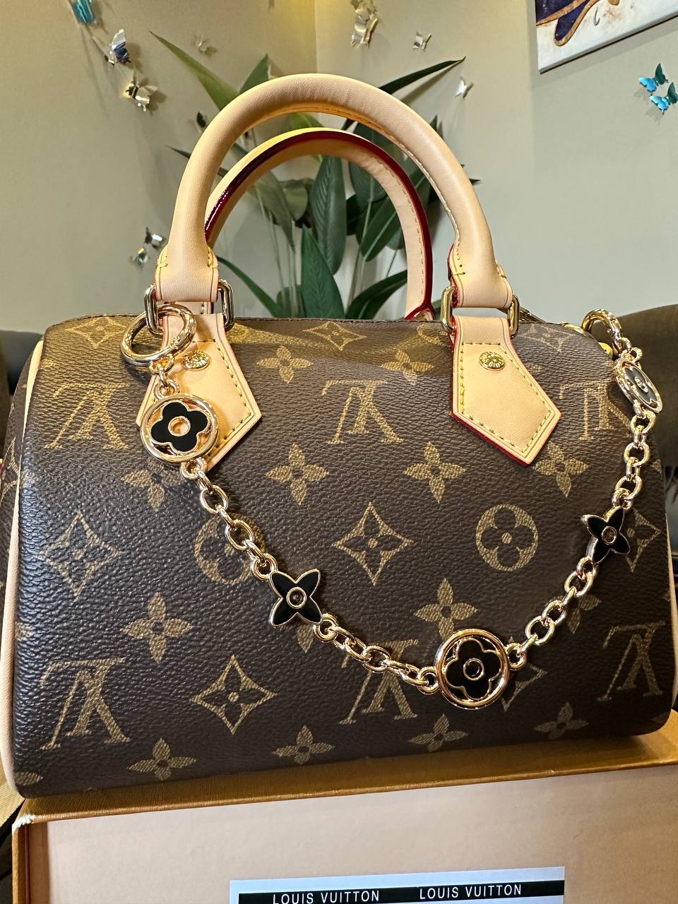 a handbag with monogram pattern and gold chain on a reflective surface.