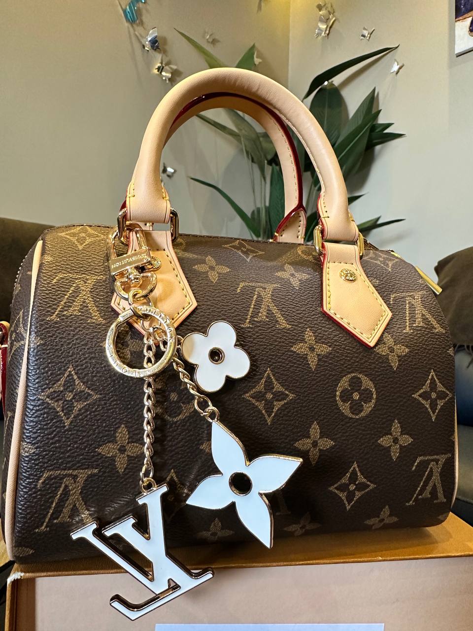 Designer handbag with monogram pattern and decorative charms on a wooden surface.